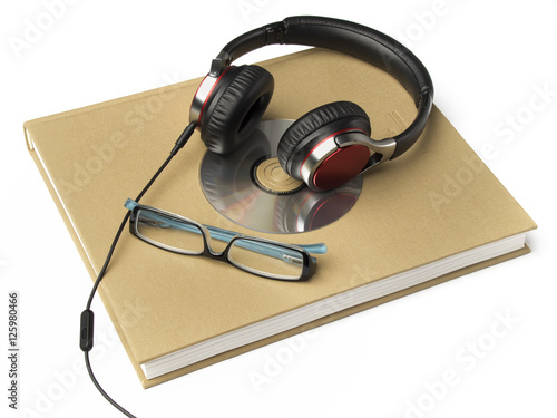 Fotografía Libro con auriculares, gafas y CD sobre fondo blanco