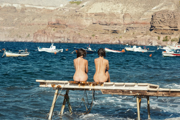 Two women sitting on pier