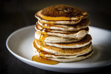 stack of golden brown pancakes on a white plate for morning breakfast or brunch