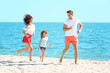 © Africa Studio - Family concept. Happy parents and daughter playing on the beach
