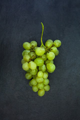 Fresh bunch of green grapes isolated on dark gray slate stone ba