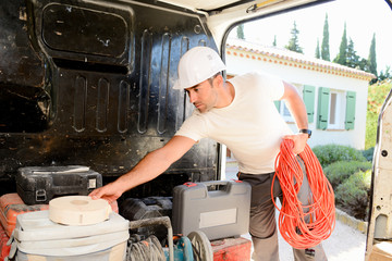 Wall Mural - young electrician artisan taking tools out of his professional truck van