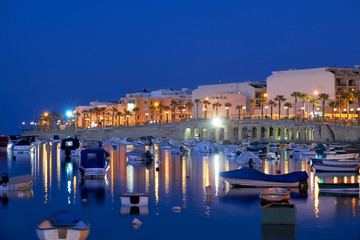 The evening view of the residential houses and hotels of Marsaskala reflecting in the water of Marsaskala Creek. Malta