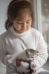 Wall Mural - Happy little Asian girl hugging lovely scottish fold kitten