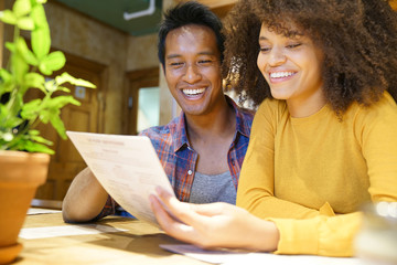 Wall Mural - Cheerful couple in restaurant choosing menu