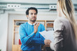 © SFIO CRACHO - Two coworkers discussing business project in modern office.Successful confident hispanic businessman talking with woman. Horizontal, blurred background.