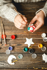 Wall Mural - Girl in a bright sweater paints porcelain figurines.