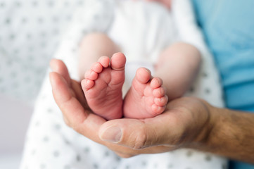 Unrecognizable father with newborn baby son, legs and hand