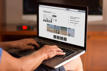 cropped image of a senior man using his laptop at home with trav