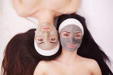 Two girls are relaxing during facial mask application in spa