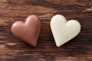 Wall Mural - Two sweet chocolate hearts on wooden background