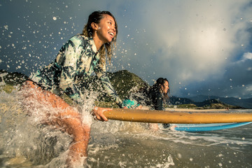 Surfing girl with surfboard in water splashes