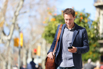 young urban businessman professional on smartphone walking in street using mobile phone app texting 