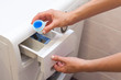 © brizmaker - She pours the liquid powder in washing machine