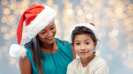 happy mother and little girl in santa hats