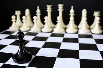 Alone chess pawn in front of enemy team. Courage and boldness. Concept with chess pieces against black background