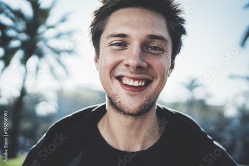 Fotografía Close-up portrait of young happy smiling hipster guy looking at camera outdoor