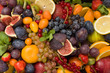 Top view on mixture of different fruit and berries: lemons, figs, grapes, tangerines, apples, strawberry, plums, red current, oranges. Healthy food concept