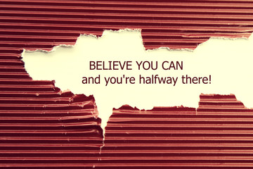 The text Believe you can and you're halfway there, appearing behind torn paper. Motivational quote.