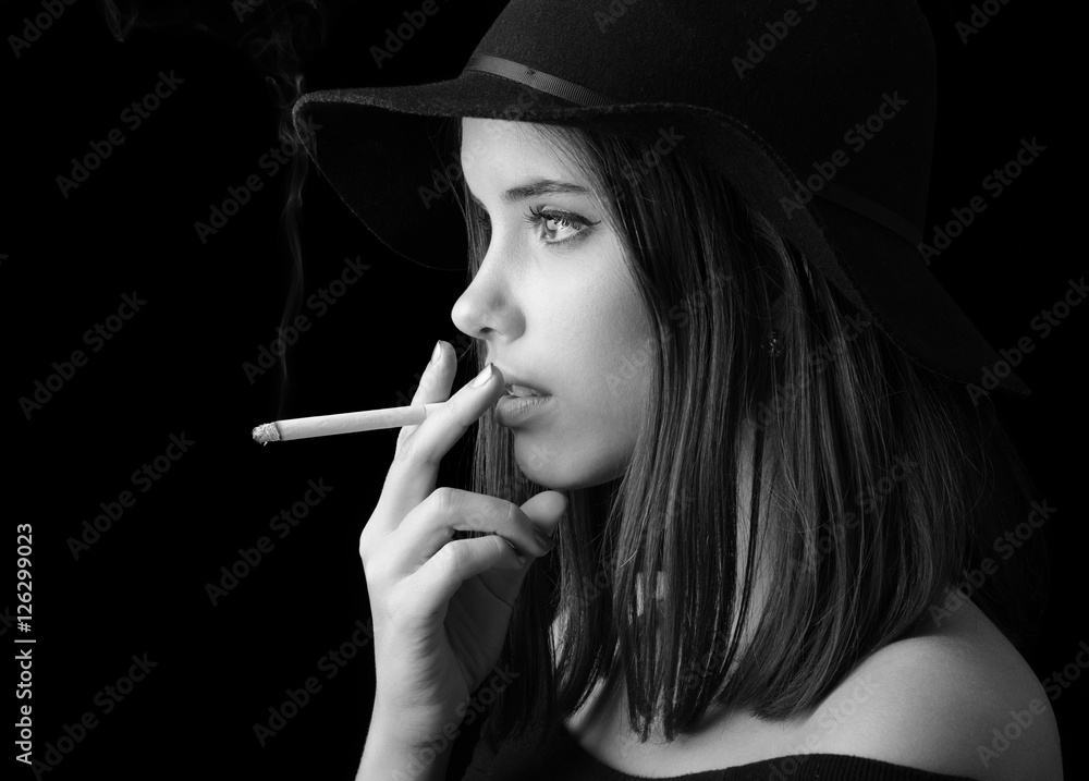 Portrait of the beautiful elegant girl smoking cigarette isolated on black  background Stock Photo
