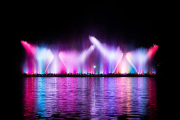 Beautiful fountain dancing show with reflection on water at night.