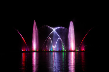 Beautiful fountain dancing show with reflection on water at night.