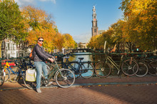 Tourist Cycling Along Canals Of Amsterdam