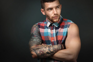 Young tattooed man posing on dark background