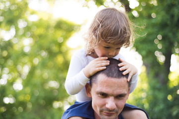 Wall Mural - Father carrying his son on his shoulders. Sunny summer.