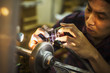 © Mint Images - A craftsman at work at a machine, etching or scoring a coloured glass object.