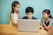 © Mint Images - A group of children in school, three children sharing a laptop computer.