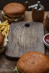 Food party table concept. Grill Sausage Sandwiches with two hamburger , potatoes fried and various sauce served on rustic table from above.