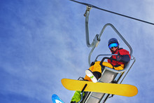 Snowboarder Sitting On Chairlift And Smiling, Close-up