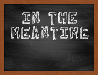 IN THE MEANTIME handwritten text on black chalkboard