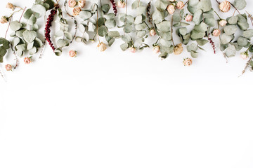 Wall Mural - Header. Eucalyptus branches and pink rose buds on white background. Flat lay, top view. Floral composition