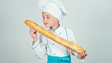 Happy Baker Girl Child Sniffing Bread Baguette Isolated On White And Smiling At Camera. Zooming