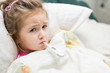 © Serhio Lee - Sick little girl holding thermometer laying in bed with grumpy face