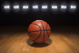 Fototapeta Sport - Basketball on wood floor beneath bright lights