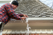 Side On Of Man Hanging Christmas Lights