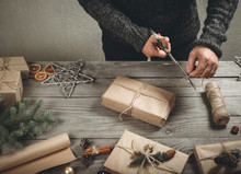 Male Hands Wrapping Christmas Gift On Wooden Table