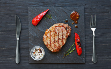 Canvas Print - Grilled beef steak on dark wooden table background, top view