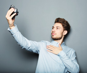 Wall Mural - Handsome young man holding camera and making selfie