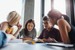 © Jacob Lund - Group of young people sitting at table reading books