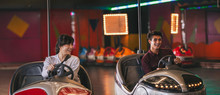 Two young friends riding bumper cars at amusement park
