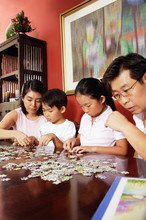 Family Of Four Sorting Jigsaw Puzzle On Table