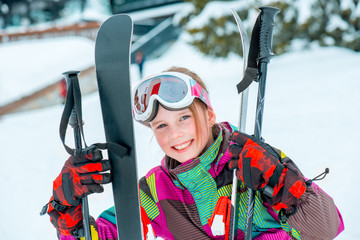 Happy kid holding skis and ski poles