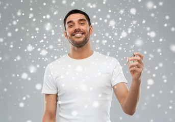 smiling man with male perfume over snow background