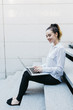 © OnAir - Businesswoman working on a laptop outdoors