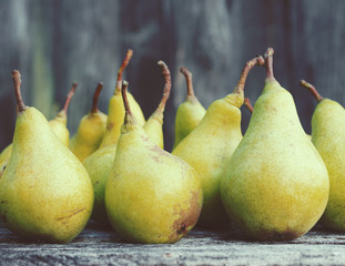 Fresh green pears against an old textural wooden surface, close up. Autumn harvest of pears