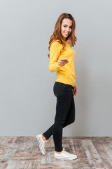 Poster - Happy smiling woman in yellow sweater with mobile phone